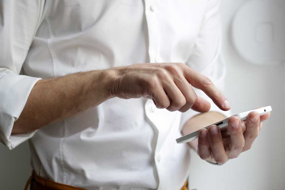 Man in white business suit texting on smart phone