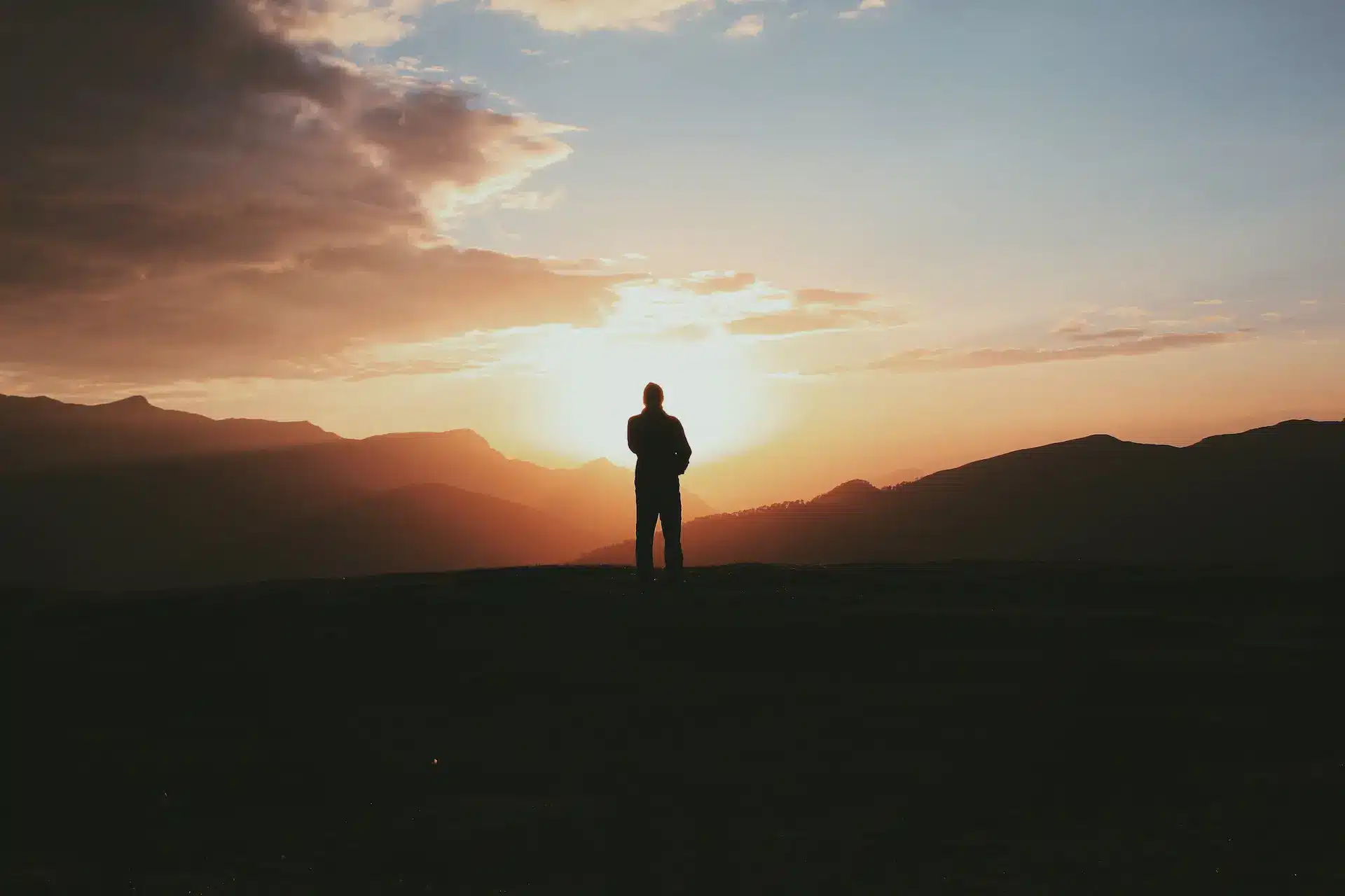 Man standing on mountain top watching glowing sunrise